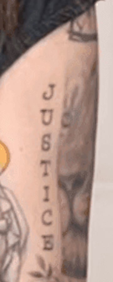 Close-up of vertical block lettering reading JUSTICE tattooed on Nancy Mace's left forearm.