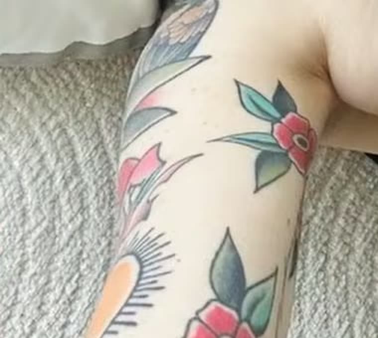 Close-up of a cluster of American-traditional roses in color, red blooms with green leaves, tattooed on Nancy Mace's right arm.